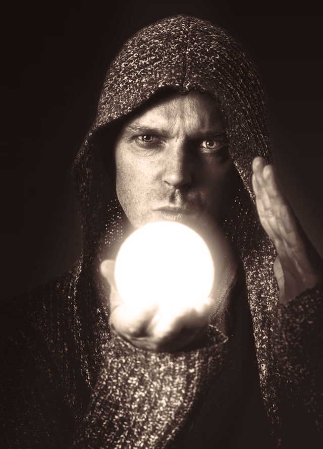 A seer waves his hand over a crystal ball.